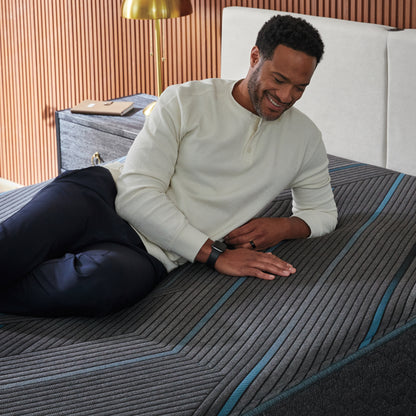 Man laying on a Beautyrest Hybrid Plush mattress on his left side rubbing his right hand on the mattress.
