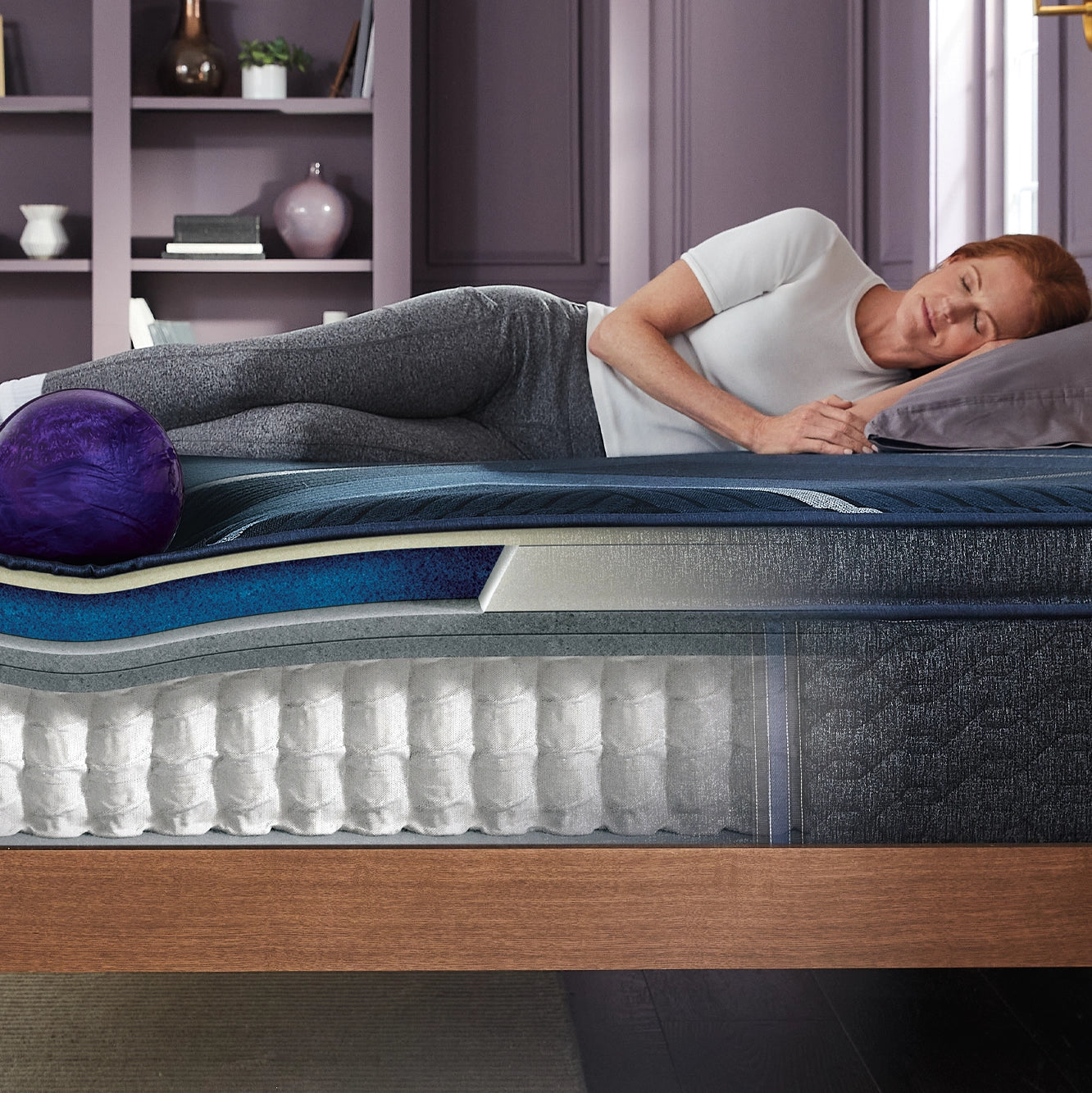 Woman laying on her left side on top of a Beautyrest mattress showing the inner working of the mattress.