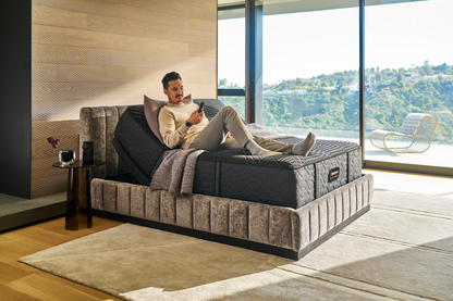 Man sitting on a Beautyrest Black mattress sitting in a Beautyrest Black Luxury Base slightly elevated at the top